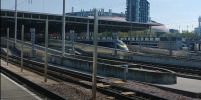 Photo taken from a SouthEastern Highspeed platform towards a departing Eurostar train, 4 posts are visible sticking out of the ground in a line between the two tracks