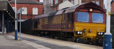 A photo of 66059 passing Wigan Wallgate, a figure of a person is visible to the left, near the stairs.