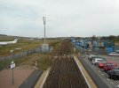 An image of two railway tracks, two platforms. On the left there is the view of a bmi regional aircraft, to the right cars in a car park.