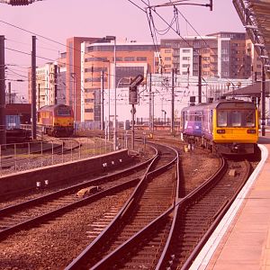 A 'Thunderbird' and a Class 142 stand at the far side of the station.