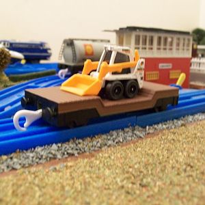 Re-painted Plarail Lowmac wagon, with a Matchbox, skid steer shovel load. 
The Lowmac is a standard Tomy Thomas model, which came in green livery (th