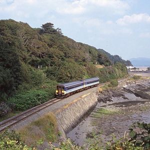 An unidentifiable pair of 153 railcars skirt the beautiful Dyfi estuary near Penhelig working a mid afternoon service from Machynlleth to Pwllheli, Ju