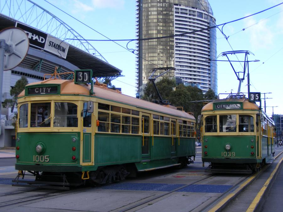 Two cream and green W class trams at Docklands next to Etiha'd Stadium.
