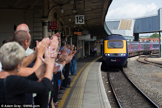 Round of applause: A crowd cheers as Bruce arrives at his final destination after 52 years as a train driver