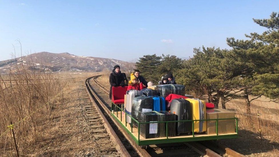 Russian Diplomat and family pushes a rail trolley of luggage through North Korea.